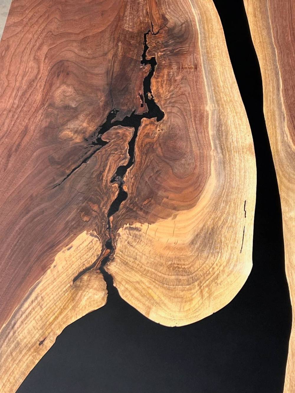 Close detail of black epoxy filling a natural void in the walnut slab