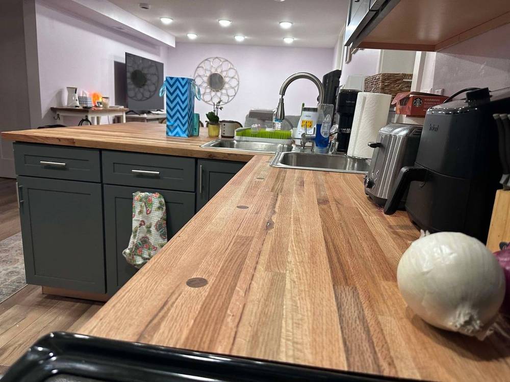 Kitchen with reclaimed butcher block countertop run along white cabinets