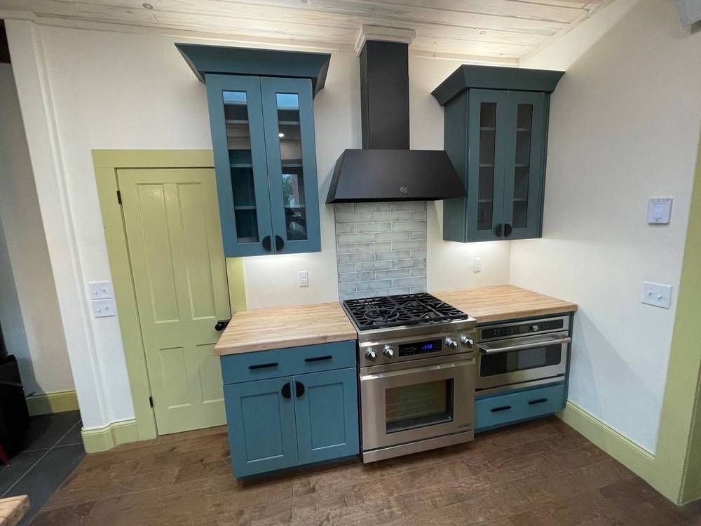 Full view of the teal kitchen with reclaimed counters