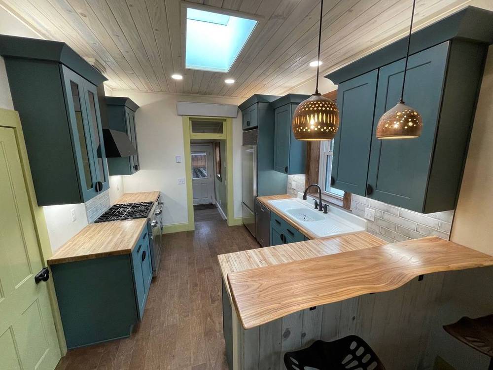 Green kitchen peninsula with reclaimed wood counter