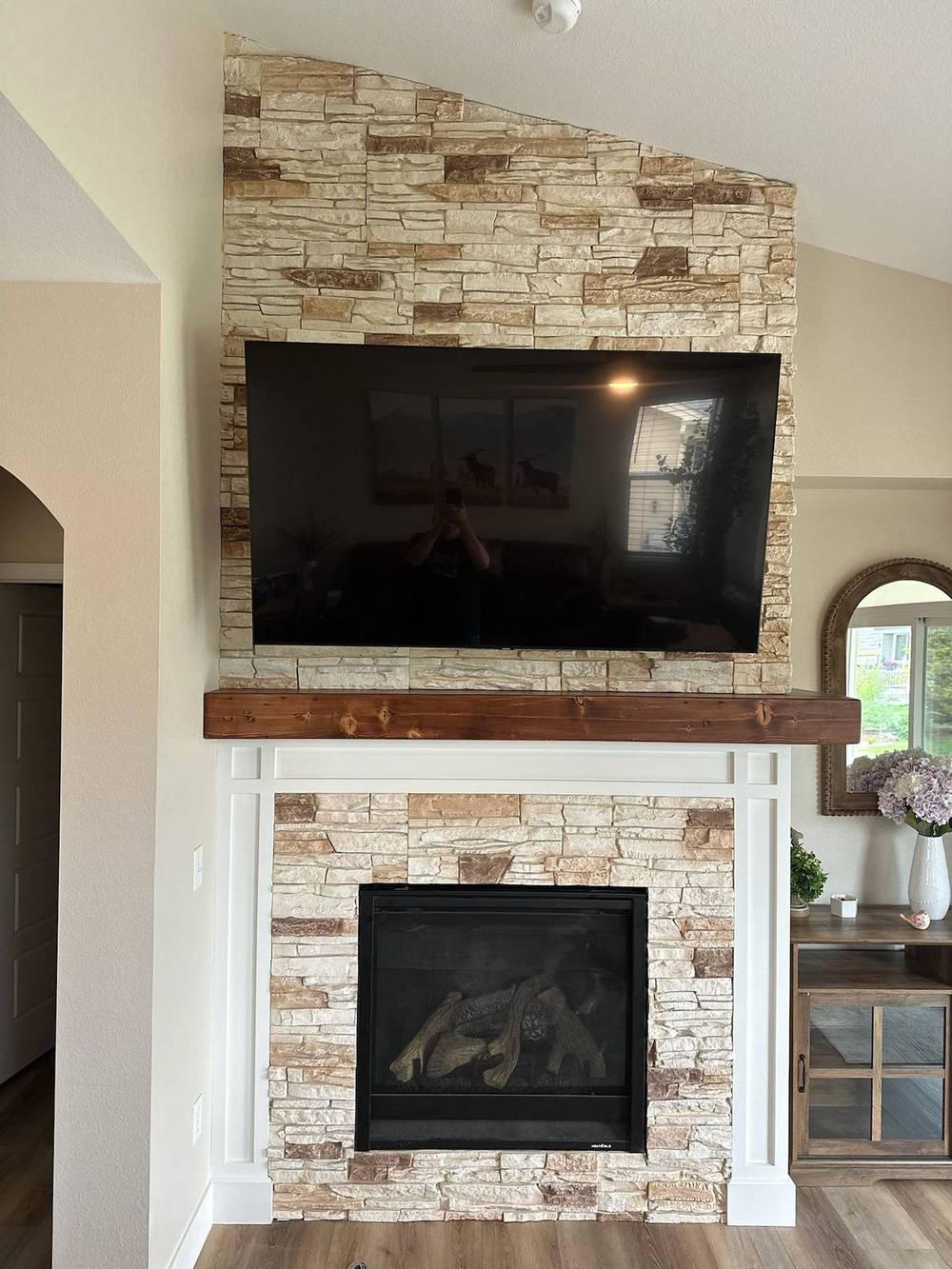 Custom reclaimed beam mantel floating above a stone fireplace