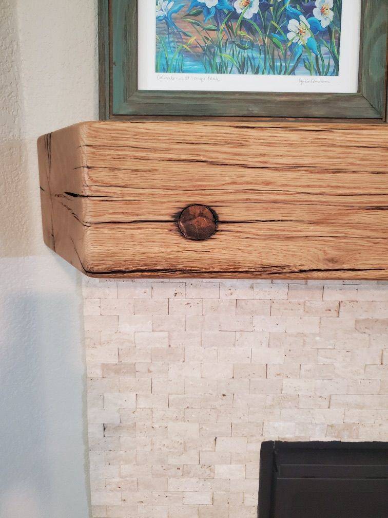 Hand-hewn barn beam mounted as a fireplace mantel, axe marks visible across the face